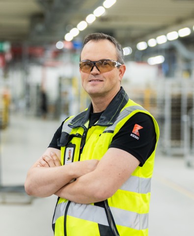 Henkilö suojalasit päässä ja huomioliivi päällä katsoo kameraan.